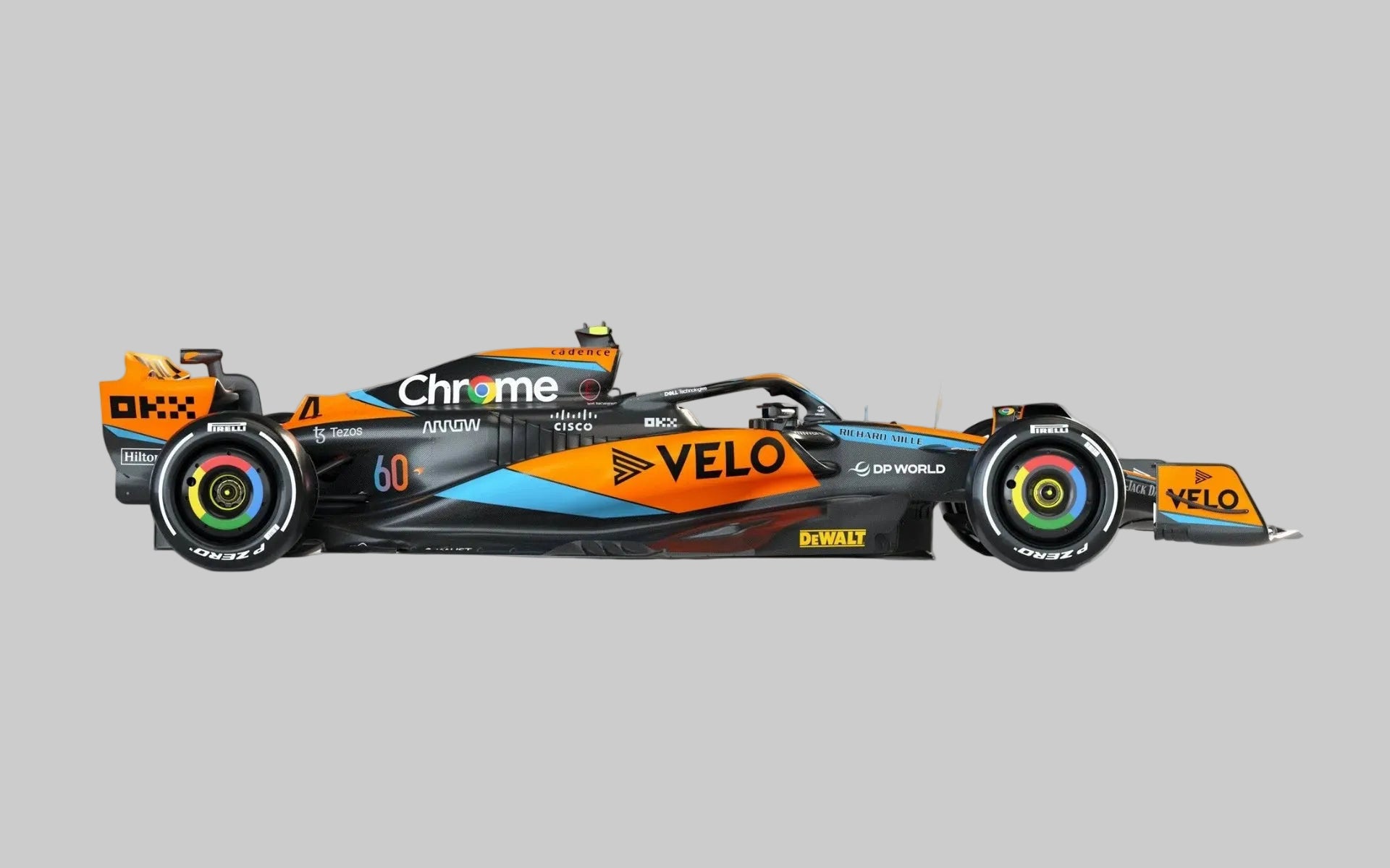 A side-profile view of an orange and black Formula 1 race car with sponsor logos including Chrome, Velo, and DeWalt, set against a clean light gray studio background.