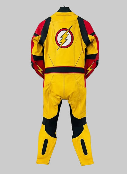 A yellow, red, and black superhero-style one-piece jumpsuit or racing suit hanging on a black hanger against a white wall. The back view shows a large circular lightning-bolt emblem on the upper back, red shoulder panels, black side sections, and yellow leg sections with black cutout details.