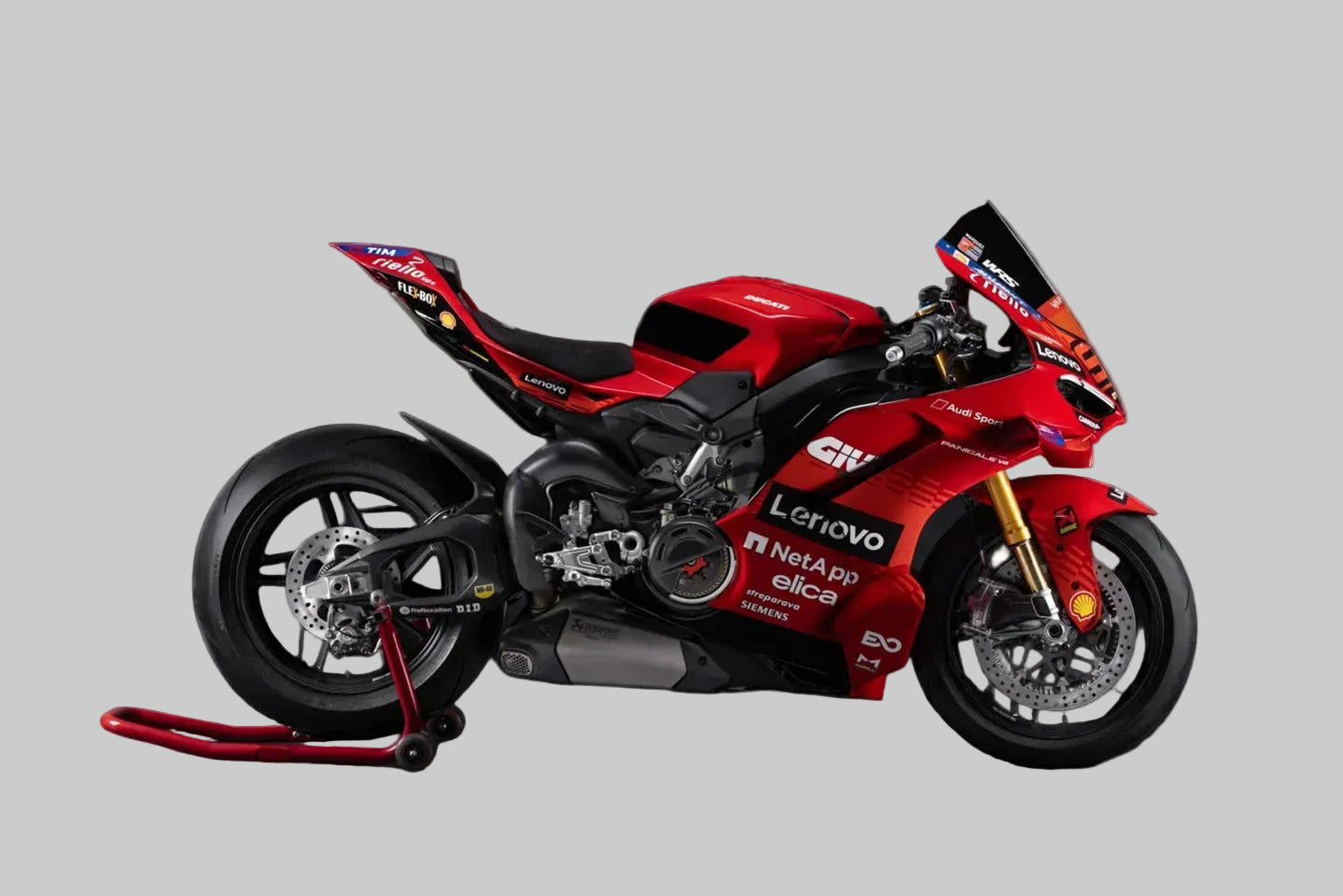 Red Lenovo Ducati sportbike motorcycle with black and white racing livery, displayed on a red stand against a solid gray background.